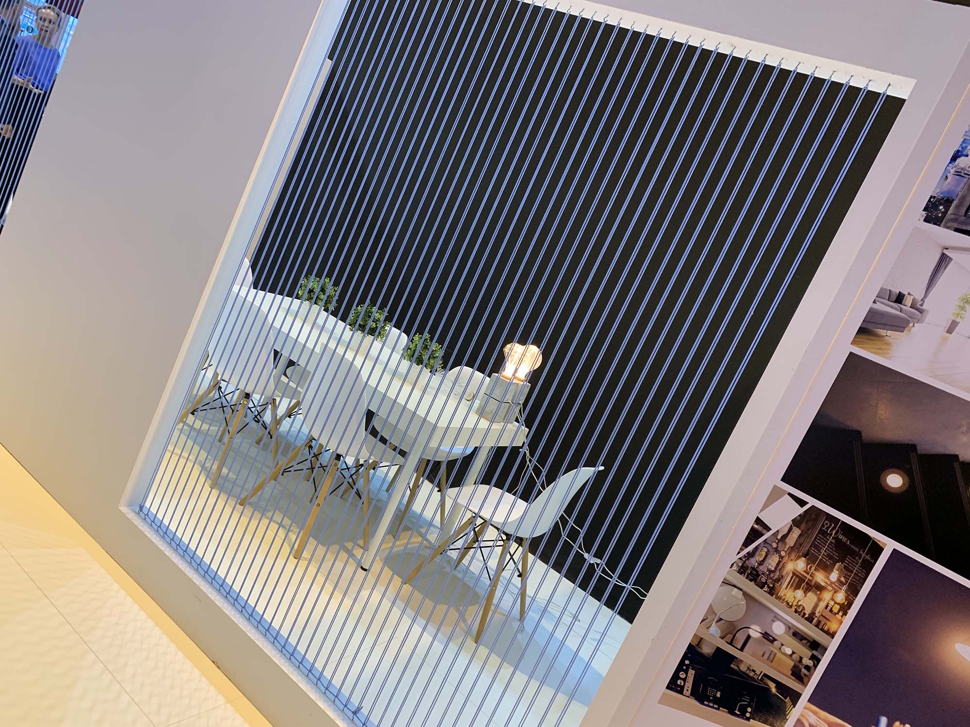 Detail of elegant exhibition stand with semi-private meeting area, vertical light-thread lattice, and white wood frame